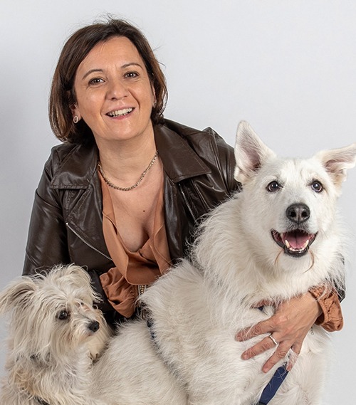 Una donna posa con due cani bianchi.