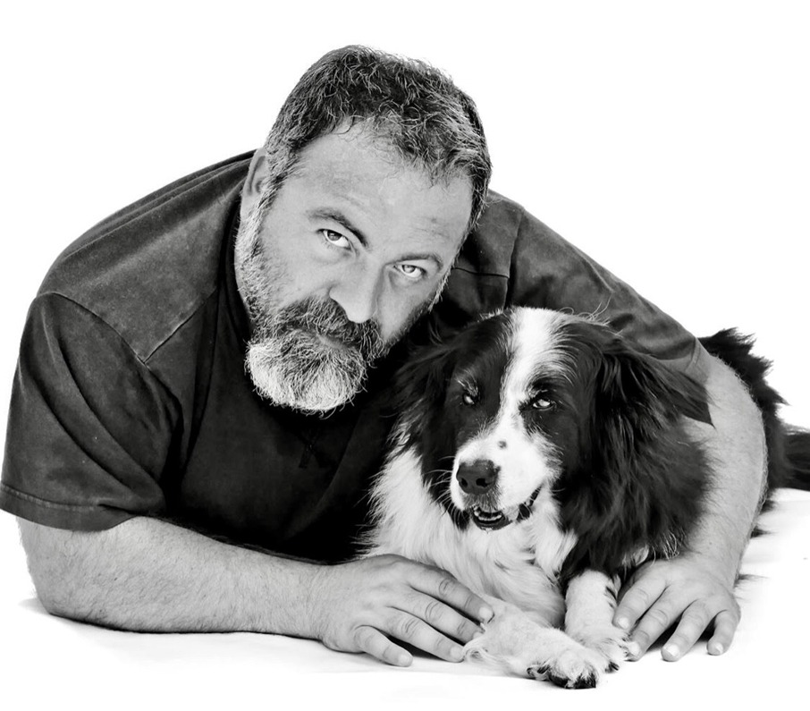 Una foto in bianco e nero di un uomo in posa con un cane.