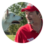 Un uomo con un cappello rosso con un cane bianco.